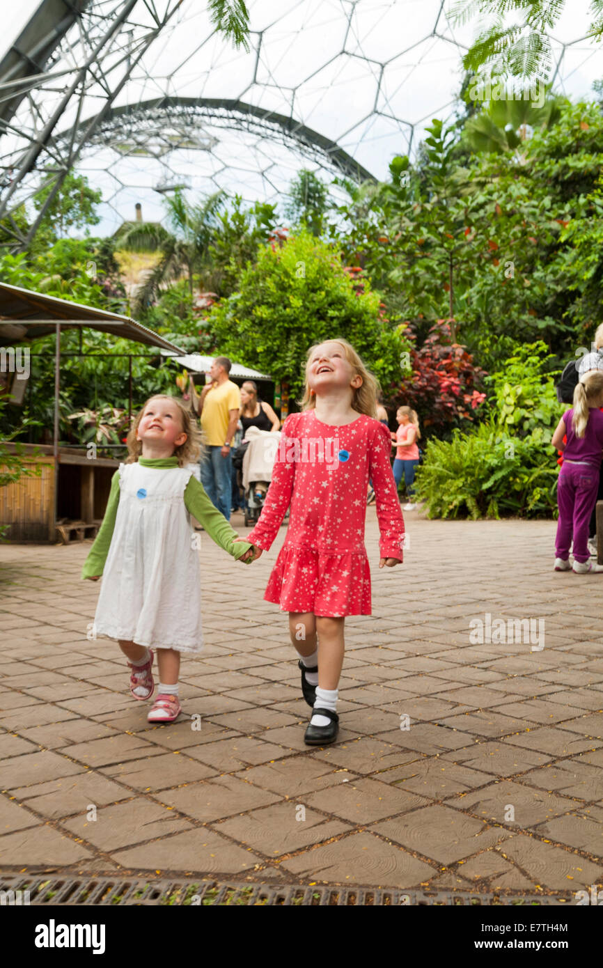 Ein zwei 2 Jahre altes Mädchen / Kind / Kinder / Kleinkinder und ihre vier 4 jährige Schwester zu Fuß / spielen in der Eden Projekt Biome. VEREINIGTES KÖNIGREICH. Stockfoto