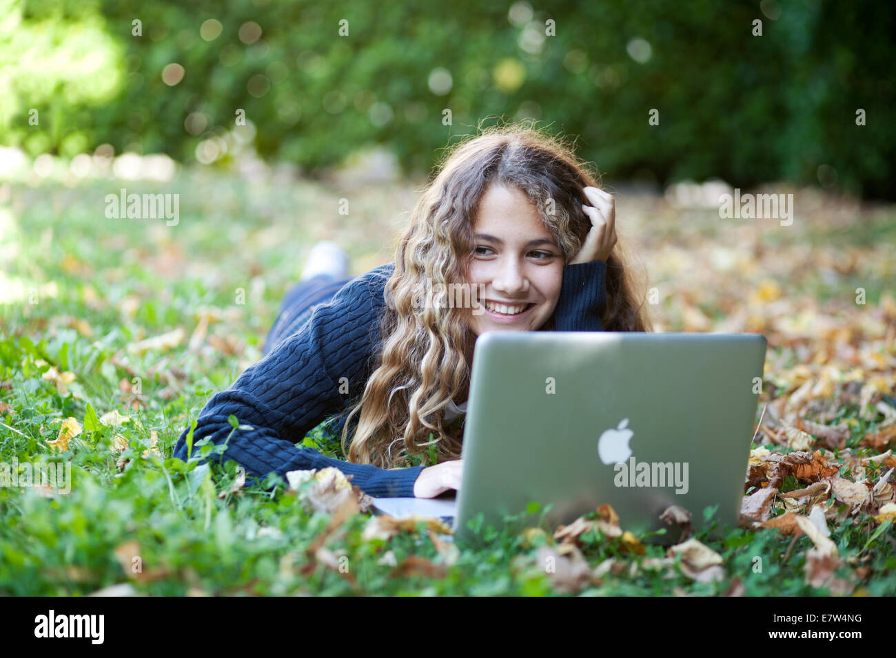 Teenager weibliche Studentin mit Laptop im Freien im Garten mit abgefallenen Blättern. Herbst Stockfoto