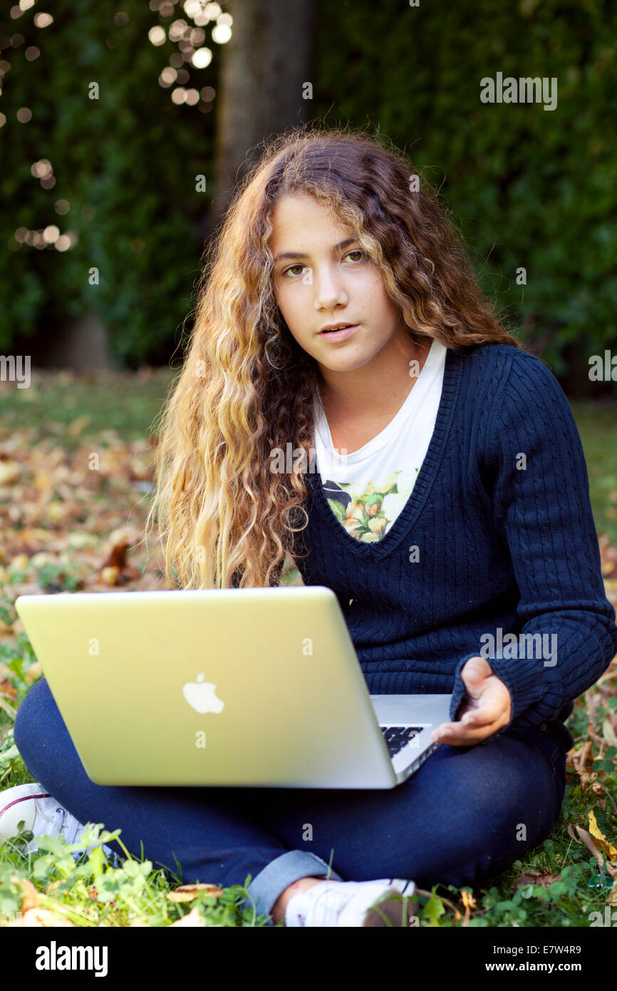 Teenager weibliche Studentin mit Laptop im Freien im Garten mit abgefallenen Blättern. Herbst Stockfoto