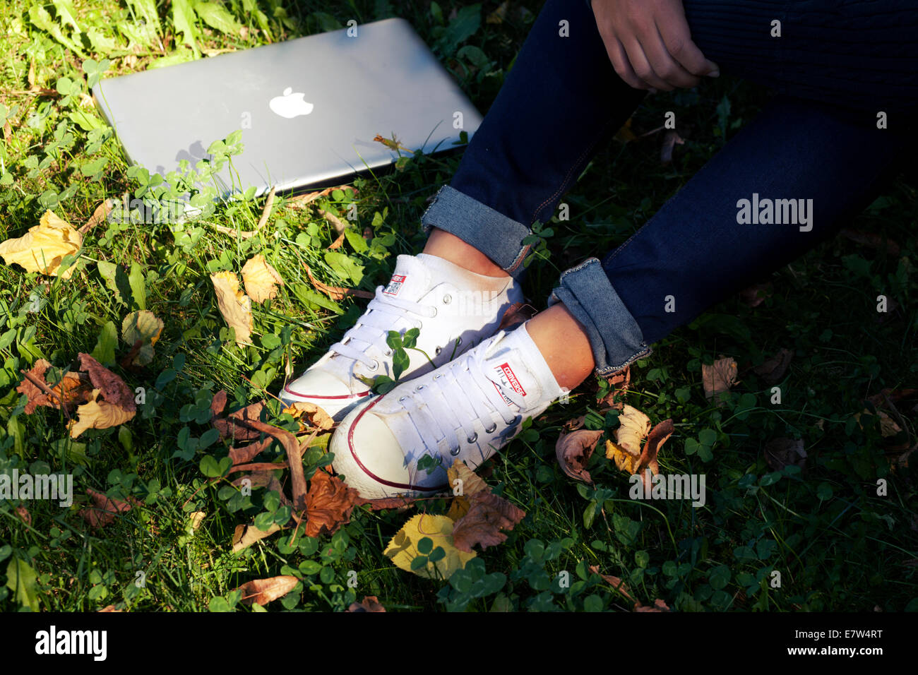 Teenager weibliche Studentin mit Laptop im Freien im Garten mit abgefallenen Blättern. Herbst-Detail auf Füßen Stockfoto