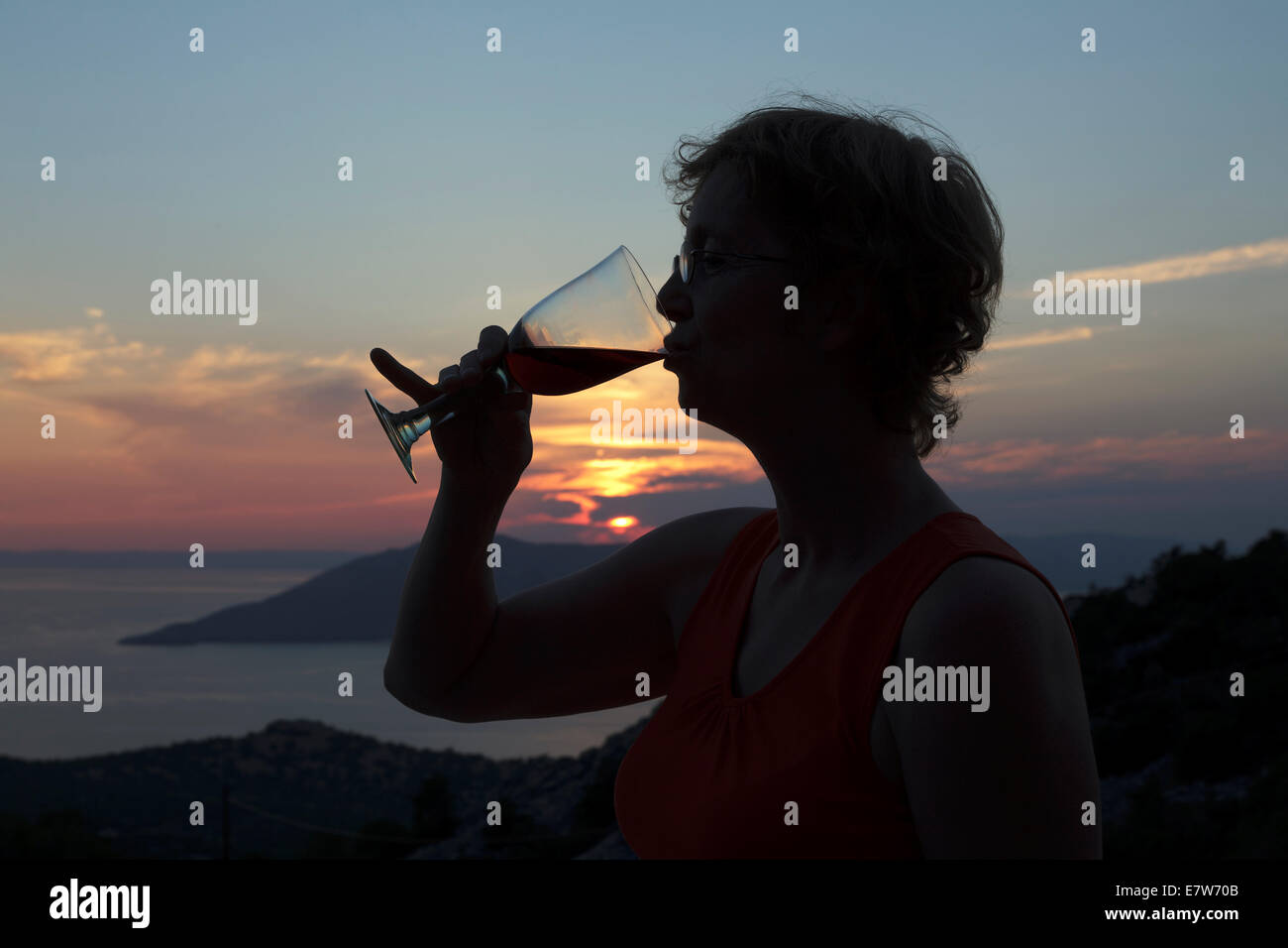 Frau trinkt ein Glas jammern genießen den Sonnenuntergang über dem Kvarner Bucht, Kroatien Stockfoto