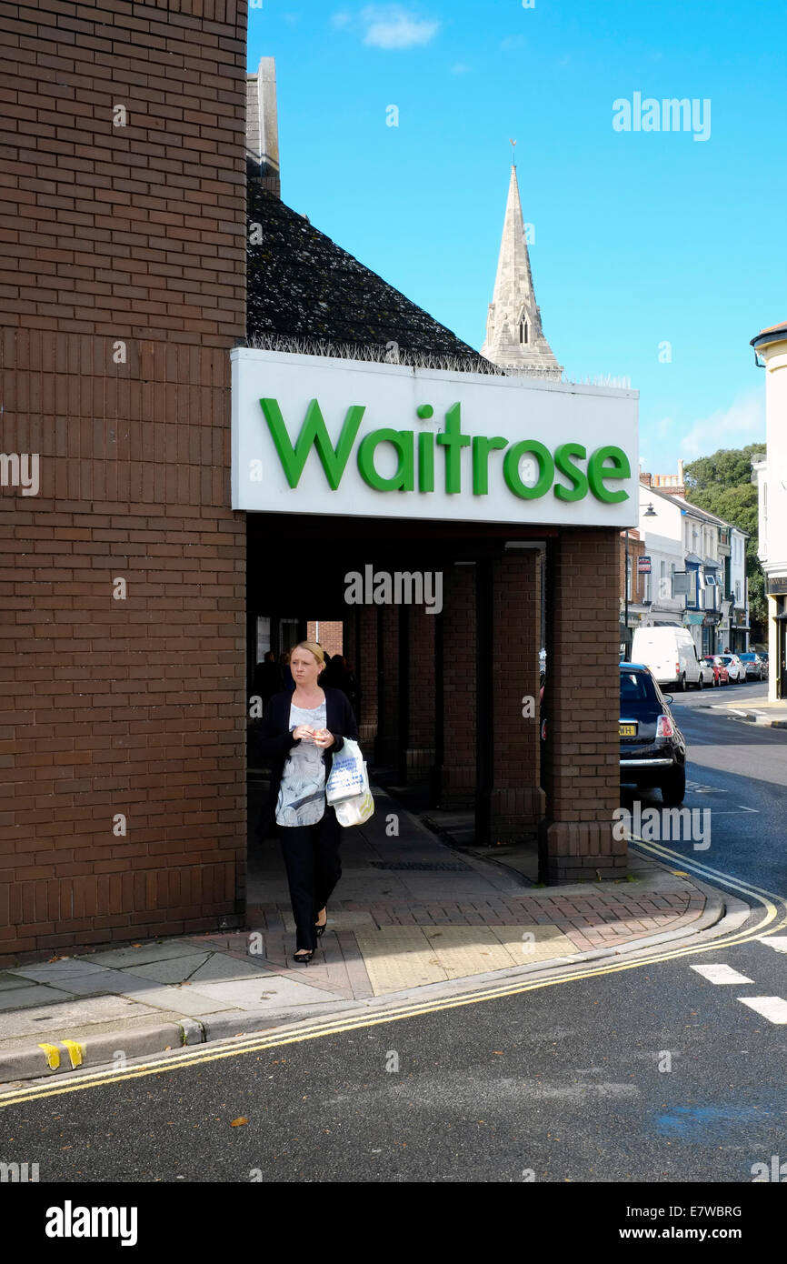 weibliche Shopper mit Einkaufstüten zu Fuß unter ein Waitrose Zeichen in Southsea England uk Stockfoto