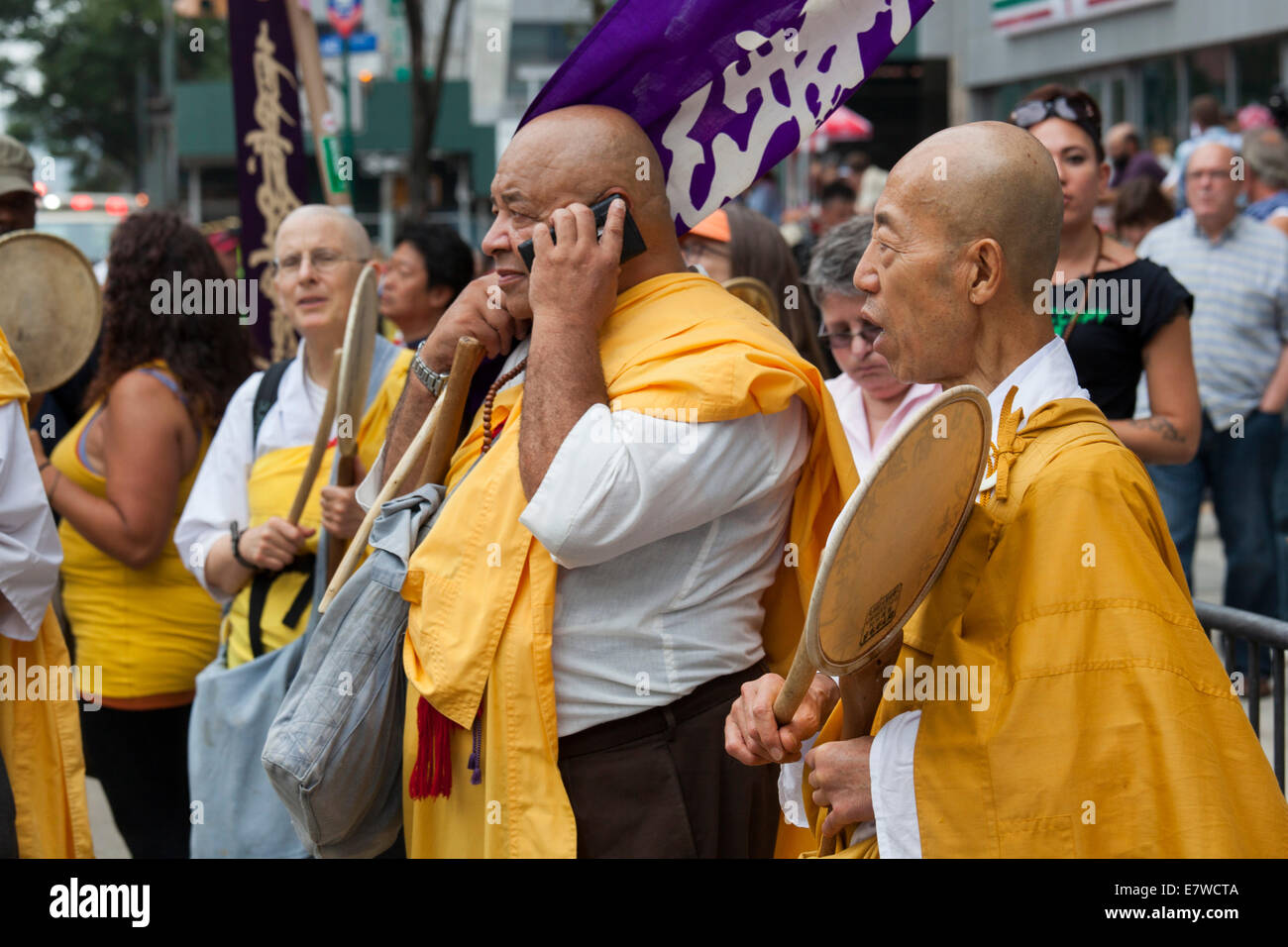 New York, New York - buddhistische Mönche Trommeln zu schlagen, während man auf einem Handy in der Nähe von Times Square spricht. Stockfoto