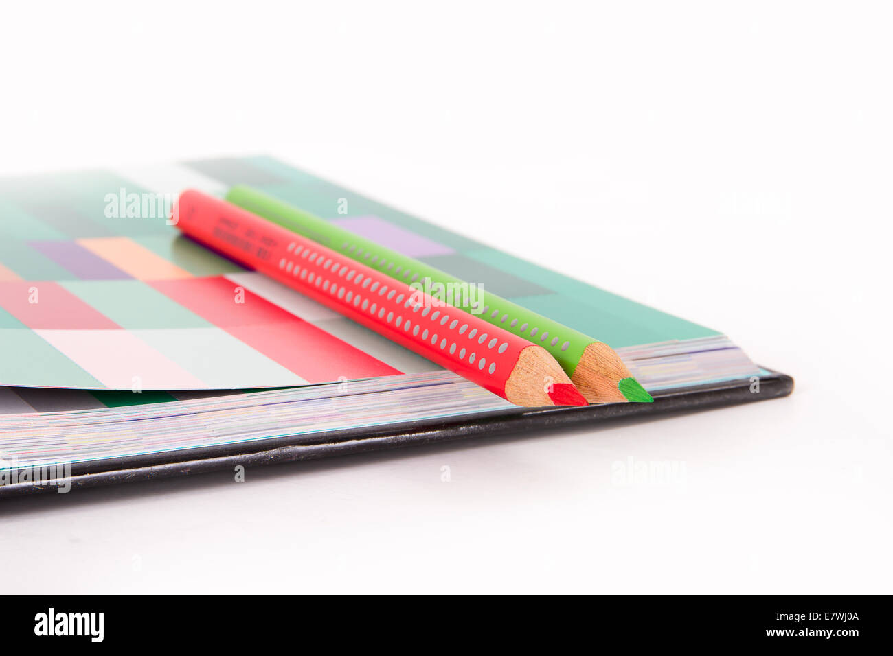 Rote und grüne Bleistifte auf bunte Palette Kunstbuch, isoliert auf weißem Hintergrund. Stockfoto