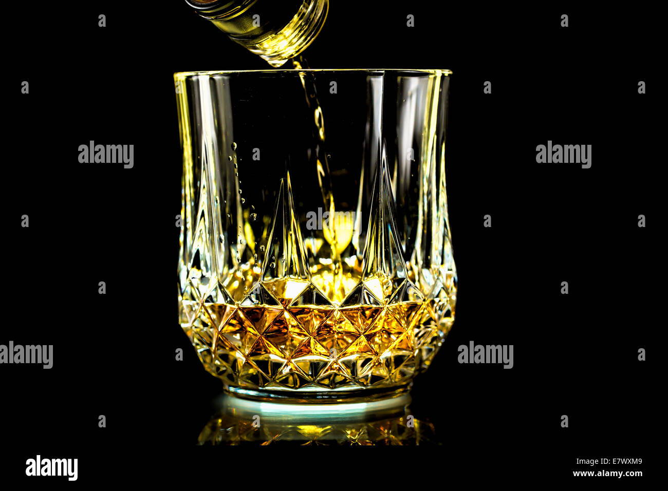 Gießen ein Glas frisch golden Whiskey aus der Flasche Stockfoto