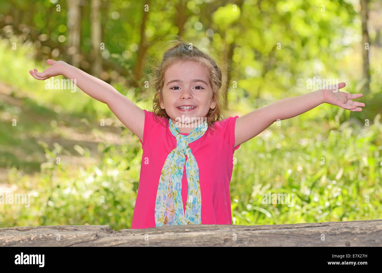 kleines Mädchen genießen und heben ihre Hände im park Stockfoto