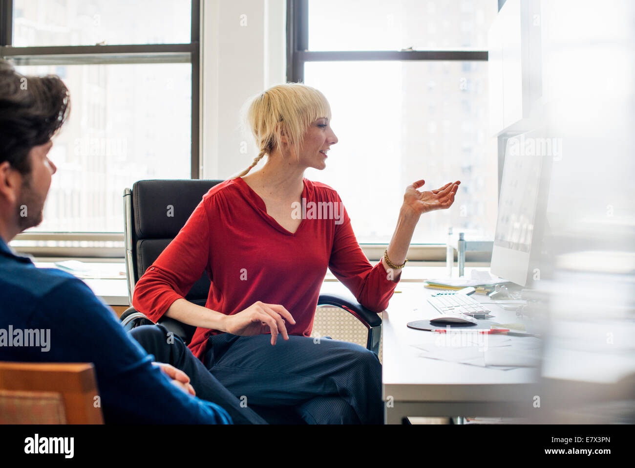 Büroalltag. Ein Mann und eine Frau in einem Büro sitzen, miteinander zu reden. Stockfoto