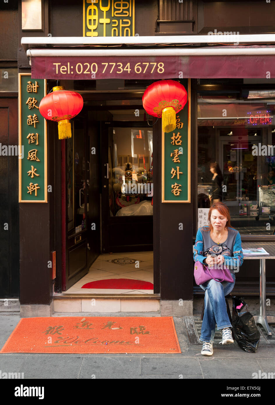 Eine Frau mit einem Mobiltelefon außerhalb ein chinesisches Restaurant, Gerrard Street, Chinatown London Soho UK Stockfoto