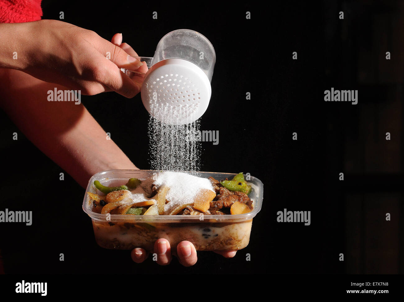 Speisen zum Mitnehmen mit Salz auf von oben gegossen wird. Hohe Niveaus des Salzes in Junk-Food verursachen, Bluthochdruck und Herz-Kreislauferkrankungen Stockfoto