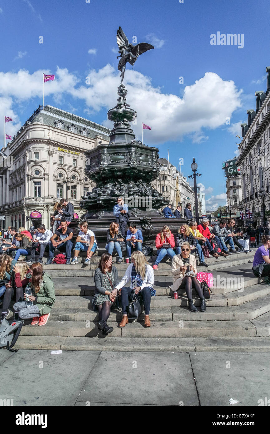 Piccadilly Circus Circus, London, Touristen sitzen auf den Stufen des Eros-Statue Stockfoto