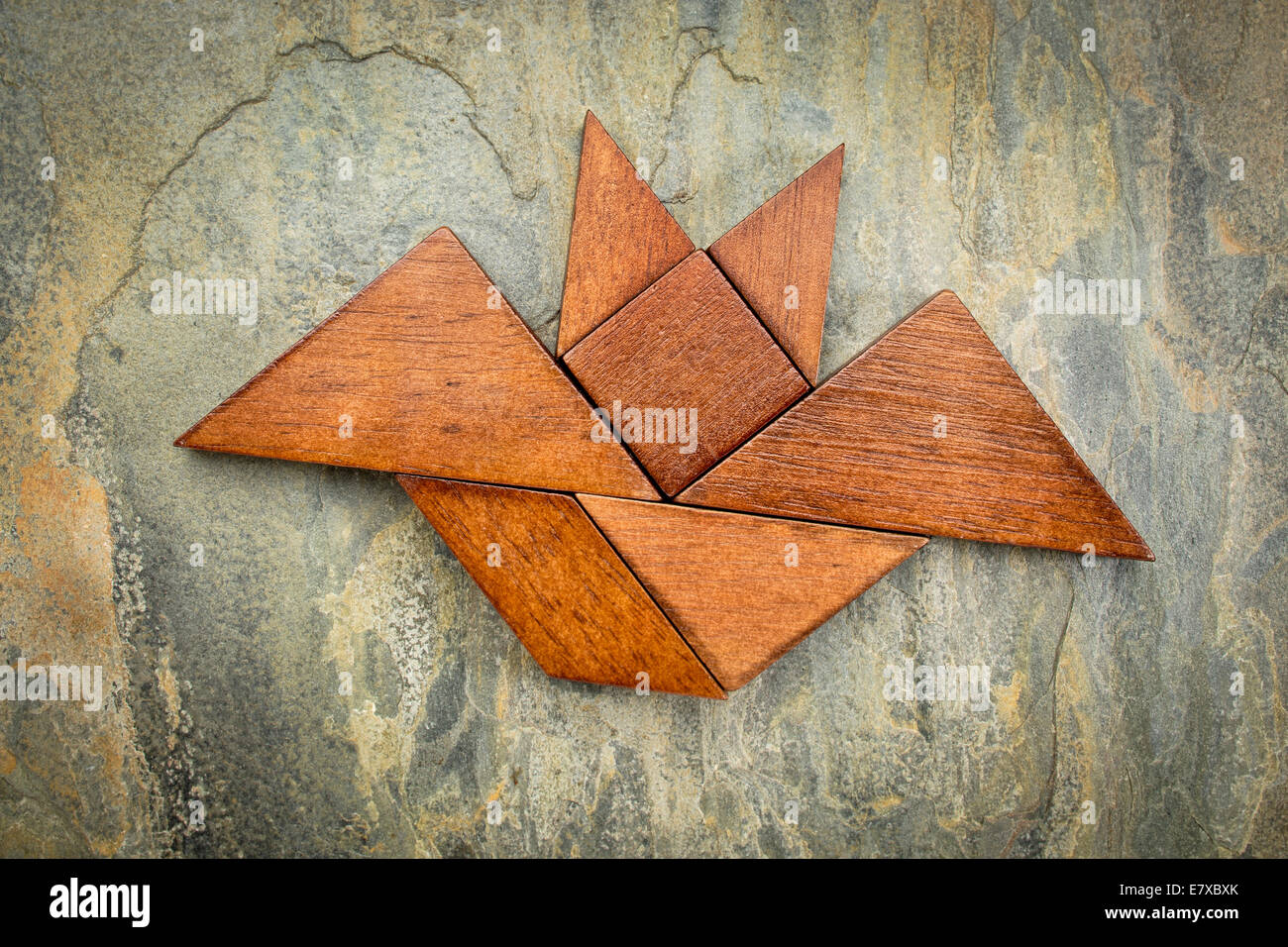 abstraktes Bild von eine fliegende Fledermaus aus sieben Tangram Holzteile über einen Schiefer Felsen Hintergrund, Halloween Konzept gebaut Stockfoto