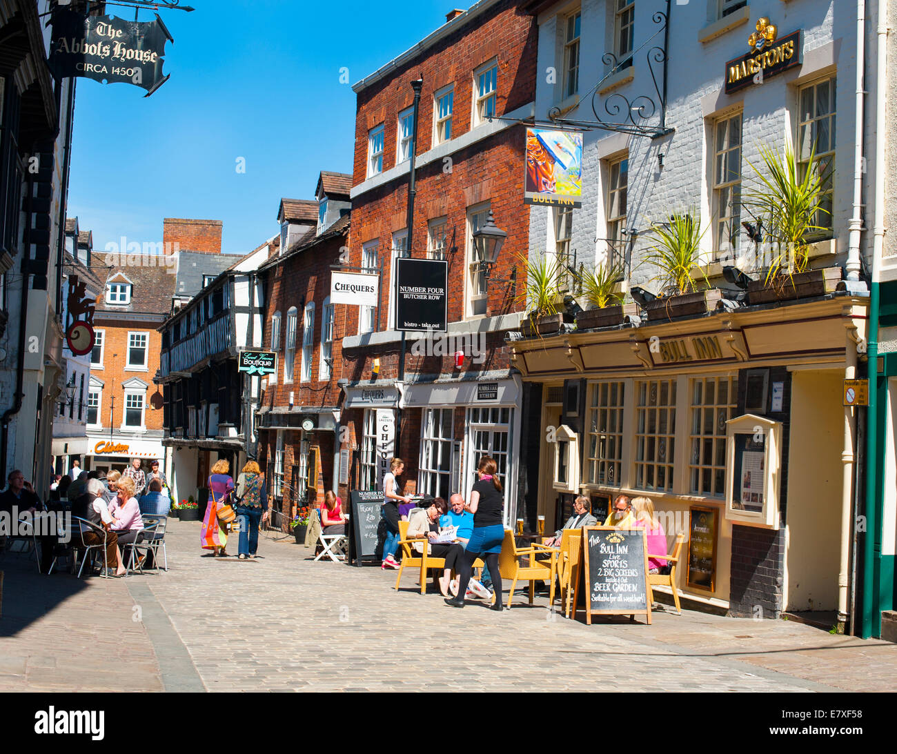 Menschen sitzen außerhalb von Kneipen und Cafés in Butcher Row, Shrewsbury, Shropshire, England. Stockfoto