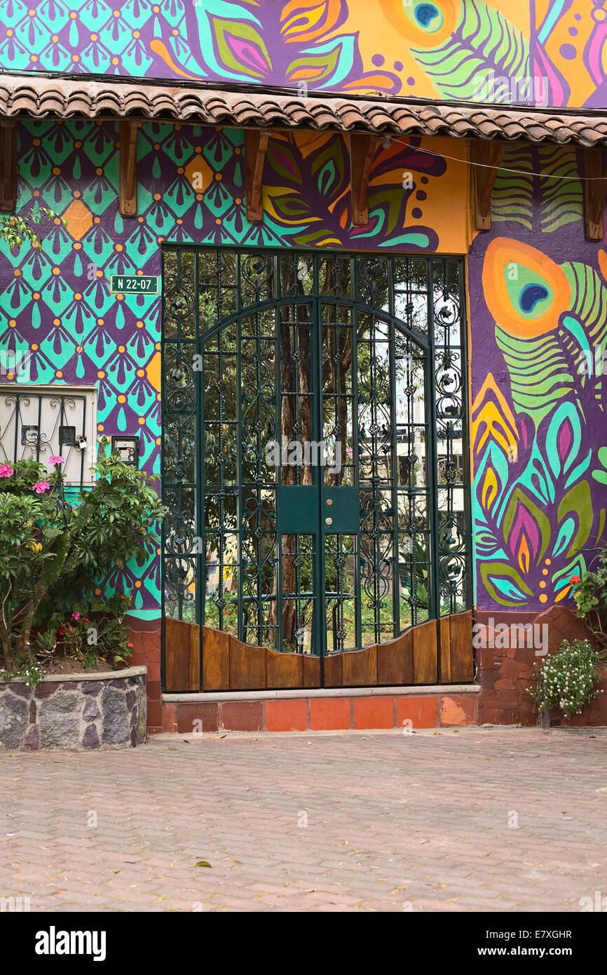 Eine Tür mit Spiegel und Metall Dekoration umgeben von bunt bemalten Wand in La Mariscal Touristenviertel in Quito, Ecuador Stockfoto