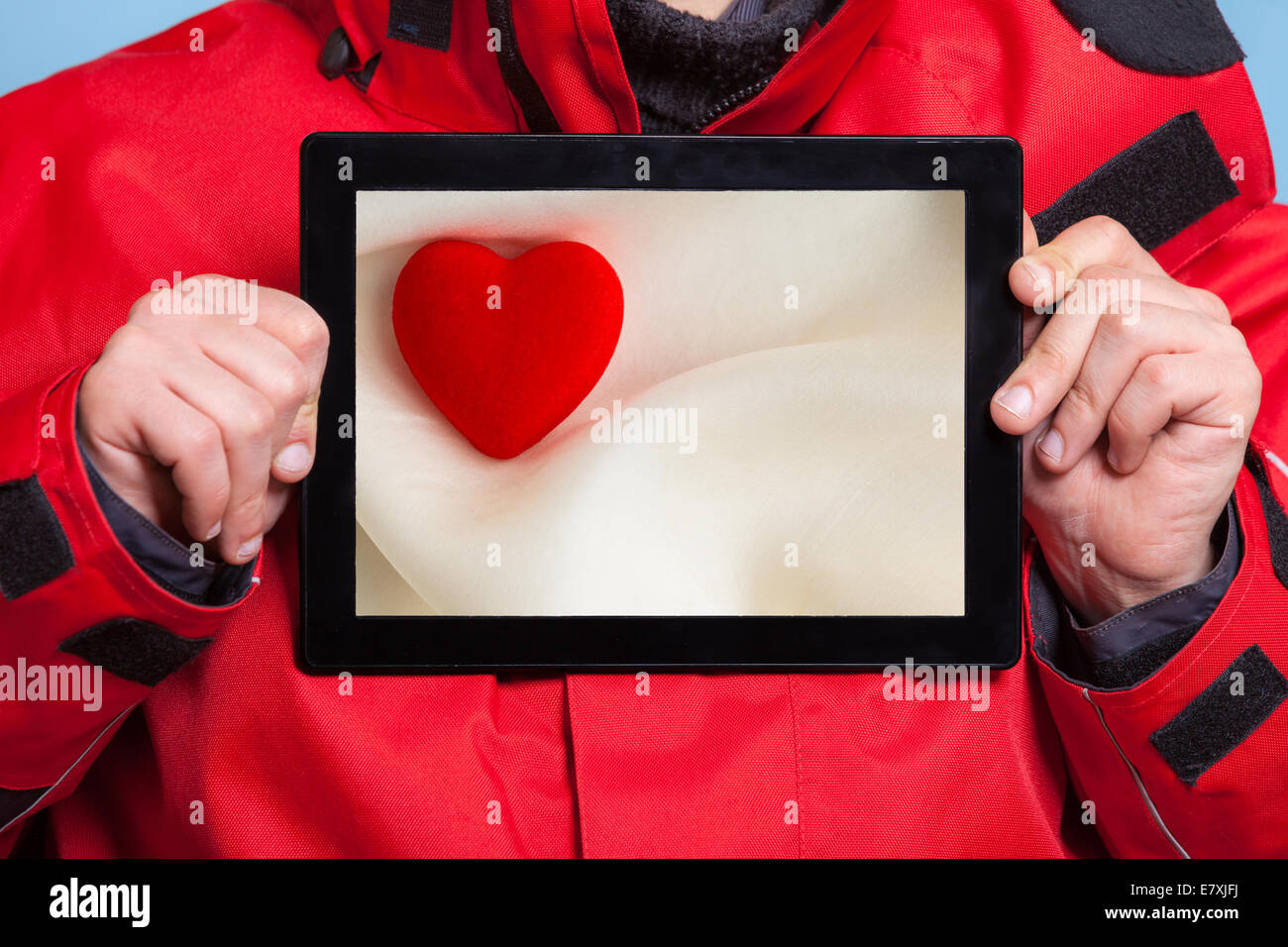 Nahaufnahme von männlichen Händen hält Ipad mit Foto von Valentine Herzen Liebe Symbol. Einsamer Mann zeigt Bildschirm Tablet Touchpad träumen Stockfoto