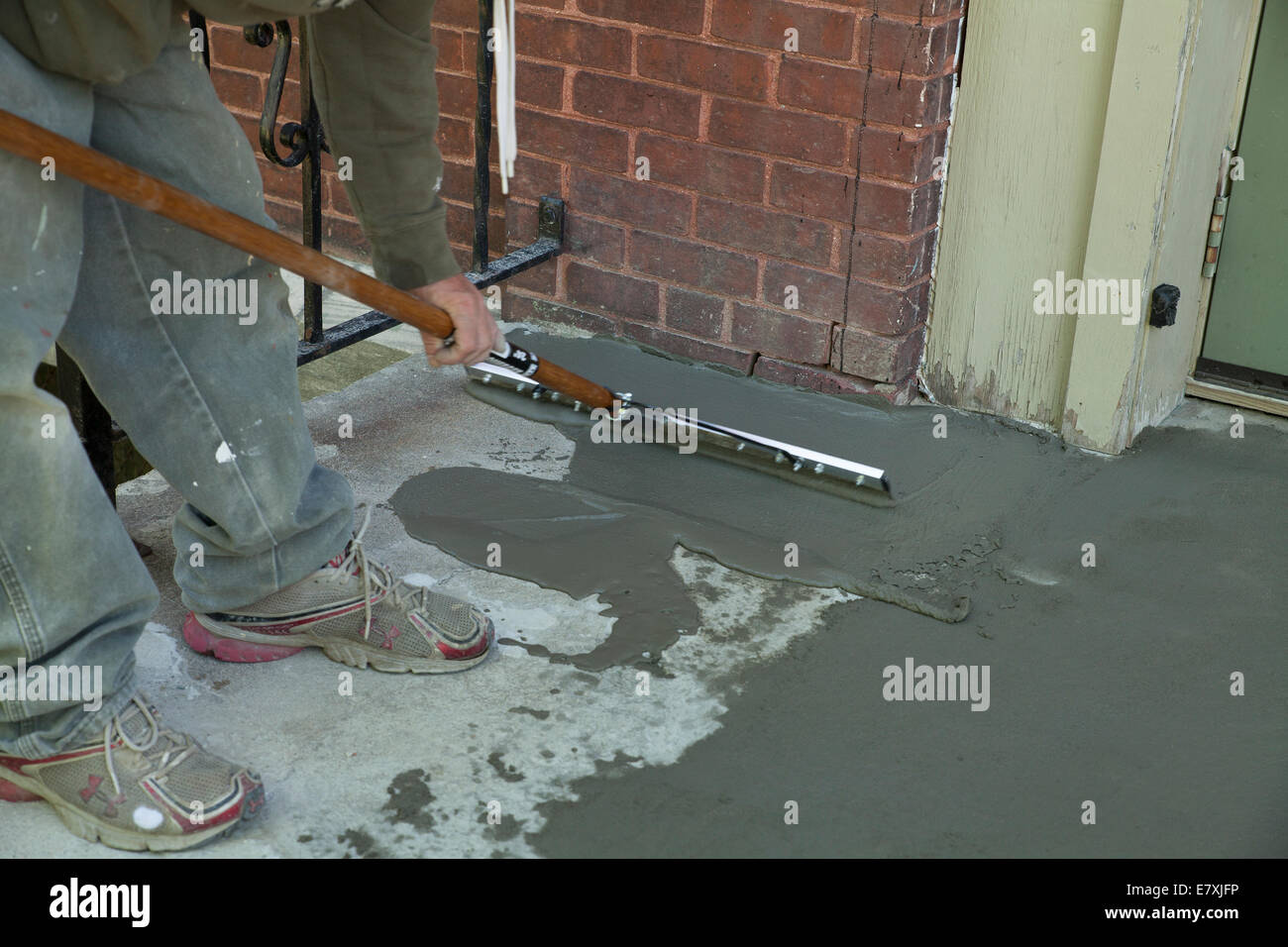 Arbeiter glättet eine Skim-Beschichtung von Zement auf alte Treppe. Stockfoto