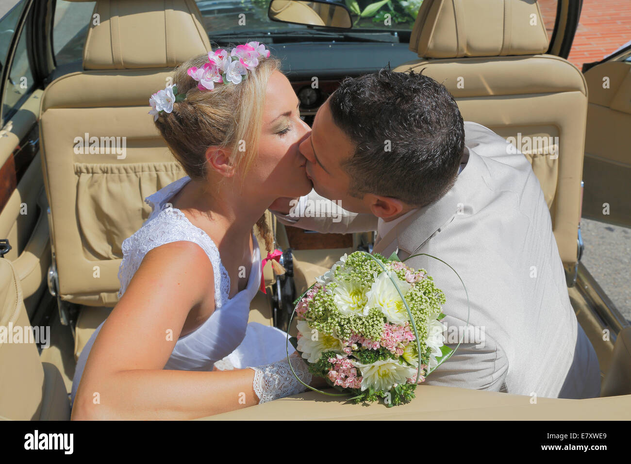 Braut und Bräutigam küssen auf dem Rücksitz eines offenen Autos, Cabrio Stockfoto