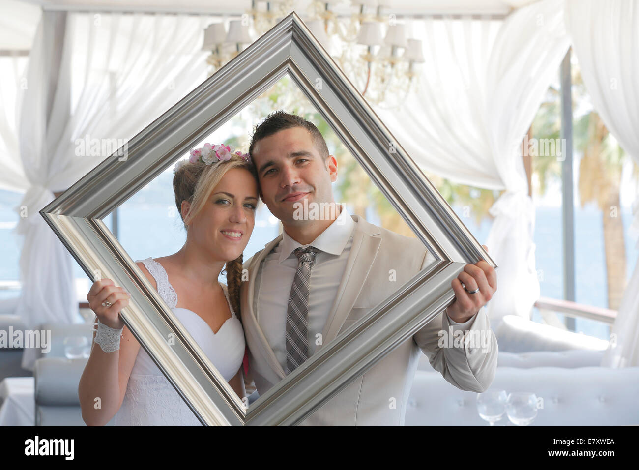Braut und Bräutigam hält ein Bild Rahmen vor ihnen und durch sie, Fotoshooting Stockfoto