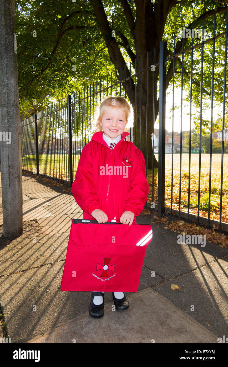 4 Jahre altes Kind / Mädchen in ihrer neuen roten Uniform, / auf dem Weg zu ihrer Rezeption Klasse am Säugling staatliche Grundschule. VEREINIGTES KÖNIGREICH. Stockfoto