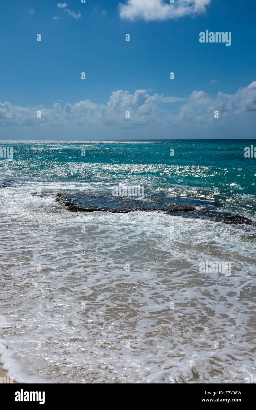 Ozean bricht über ein flaches Riff auf den Strand auf Barbados. Stockfoto