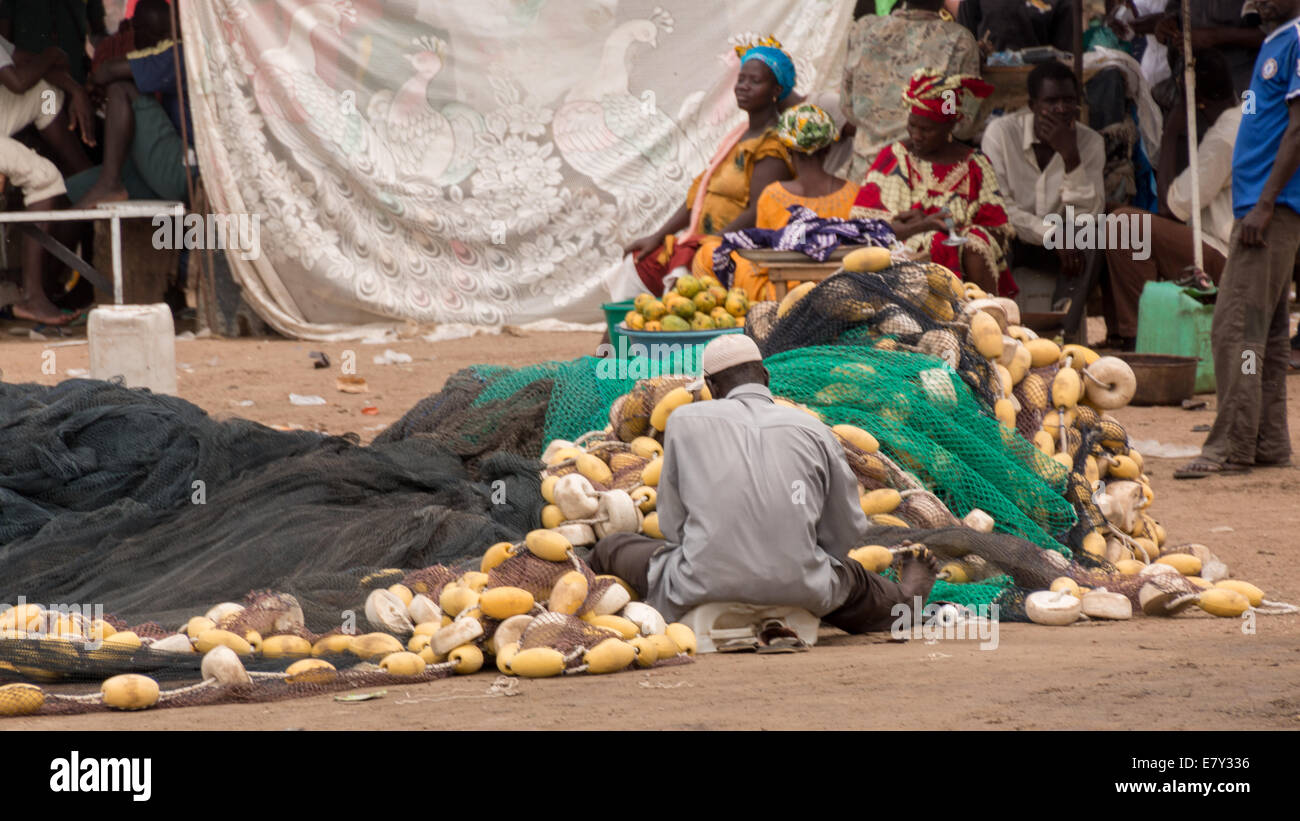 Mbour, Senegal - Juli 2014: Fischer richten Sie ihre Netze an den Stuhl auf dem lokalen Fischmarkt in Mbour am 9. Juli 2014 zurück Stockfoto