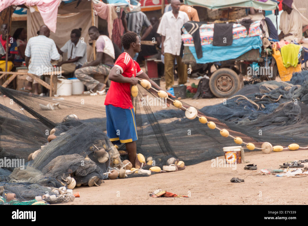 Mbour, Senegal - Juli 2014: Fischer richten Sie ihre Netze an den Stuhl auf dem lokalen Fischmarkt in Mbour am 9. Juli 2014 zurück Stockfoto