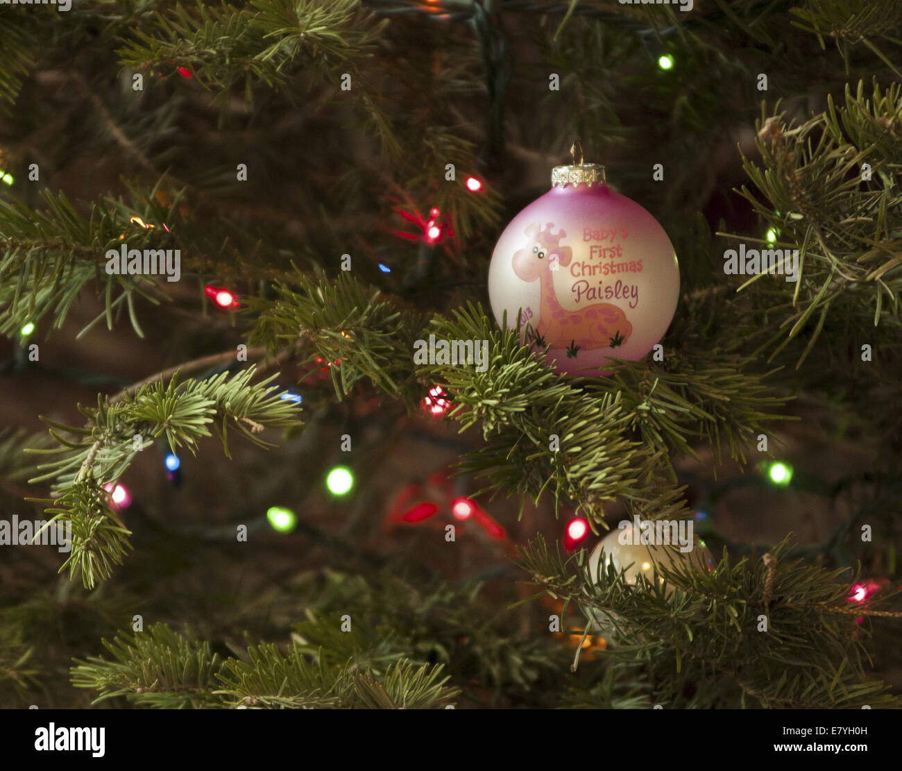 Babys erstes Weihnachten Ornament an einem Weihnachtsbaum hängen.  Es ist rosa und weiß mit einer kostbaren Momente Giraffe. Stockfoto
