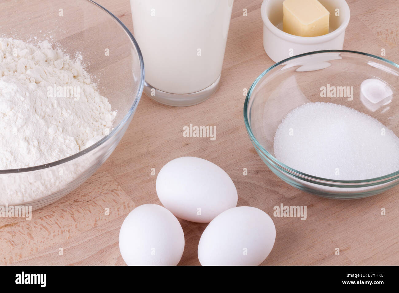 Zutaten in der Küche mit einer Schüssel Mehl, Eier, Zucker, Krug mit Milch und Butter bereit, einen Kuchen backen oder Teig backen Stockfoto