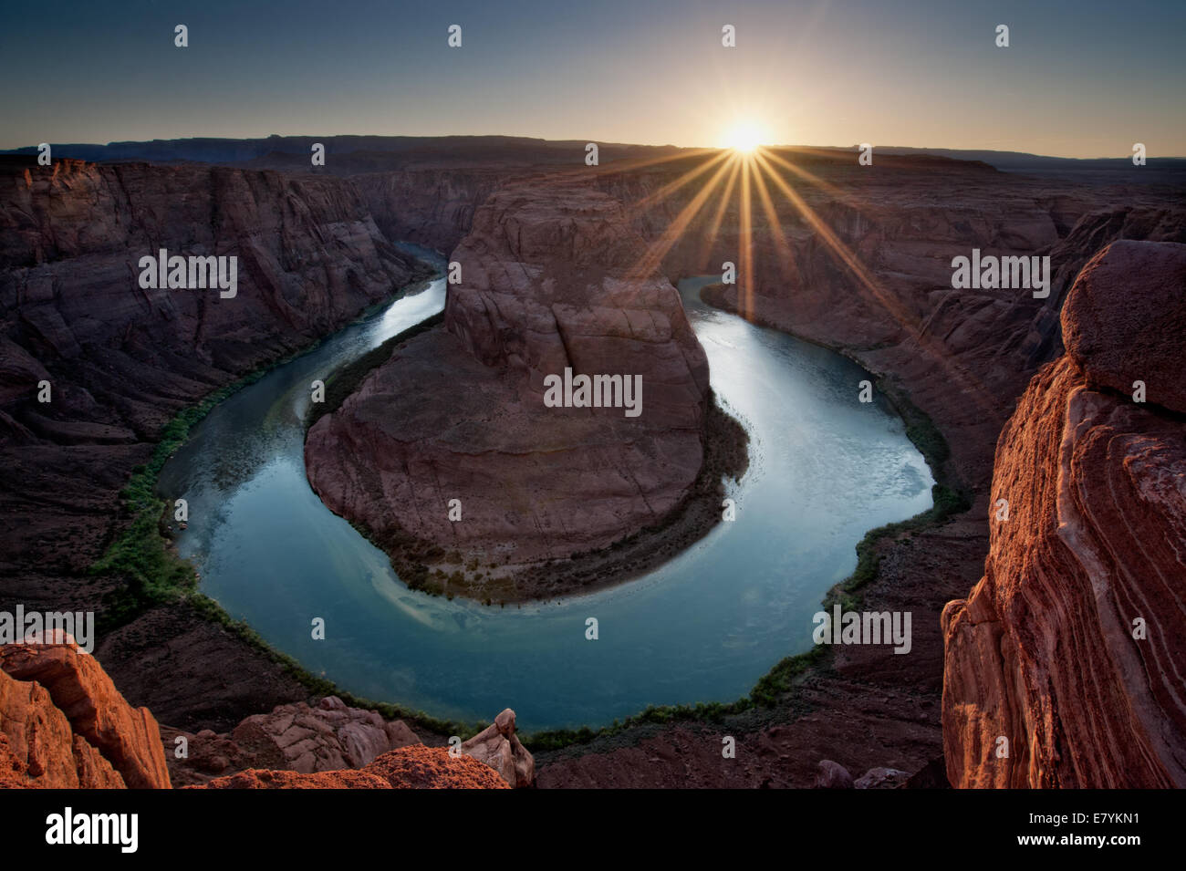 Die untergehende Sonne schafft eine markante Starburst als der Colorado River fließt um Horseshoe Bend in Arizona. Stockfoto