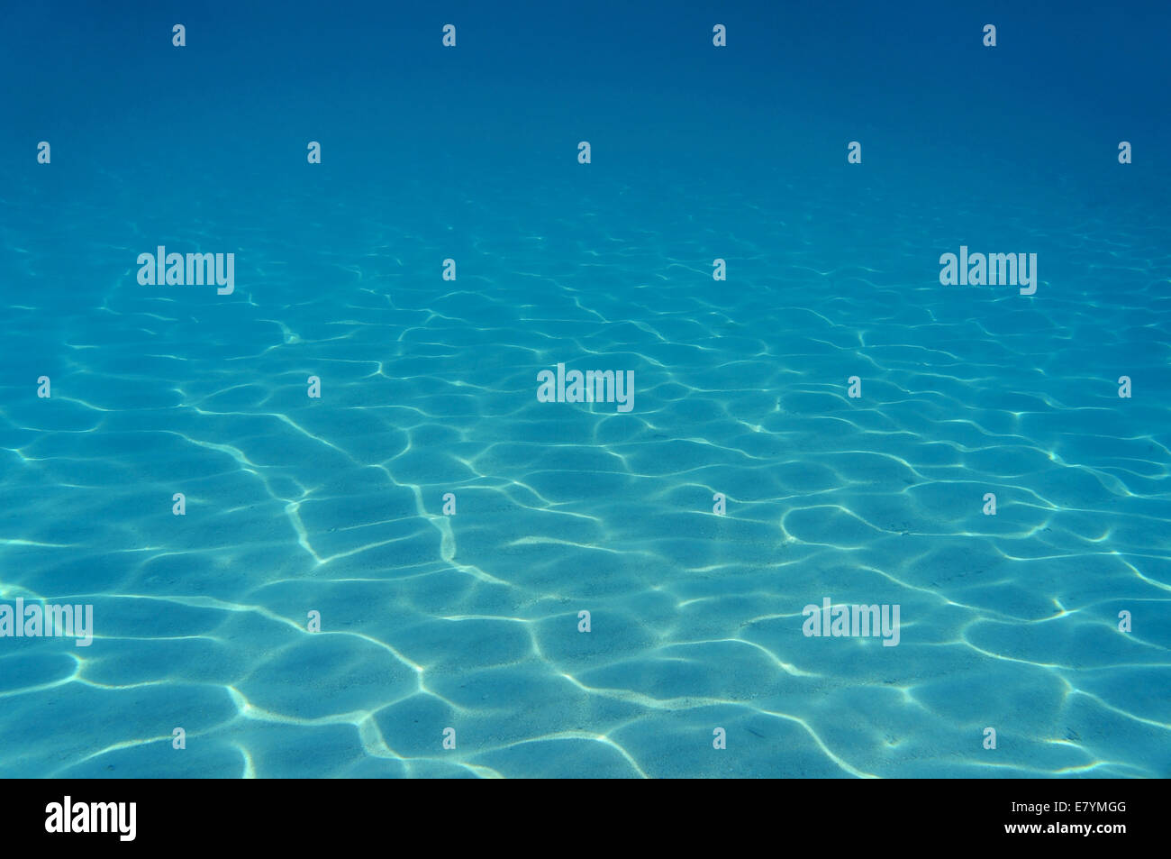 Wellen des Sonnenlichts unter Wasser auf Sandboden in der Karibik Stockfoto