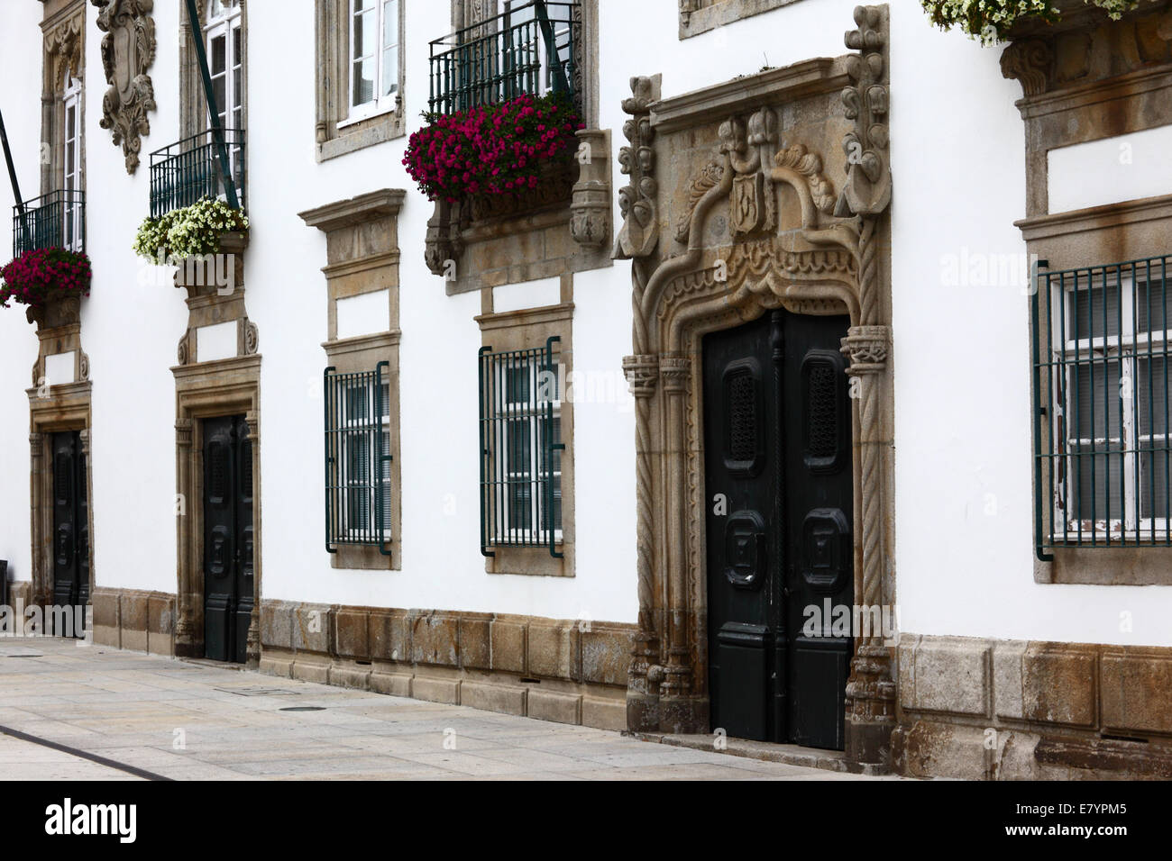 Reich geschnitzte Steintür und Fenster der Fassade der Villa Casa de Carreira mit Geranien in der Fensterbox, Viana do Castelo, Nord-Portugal Stockfoto