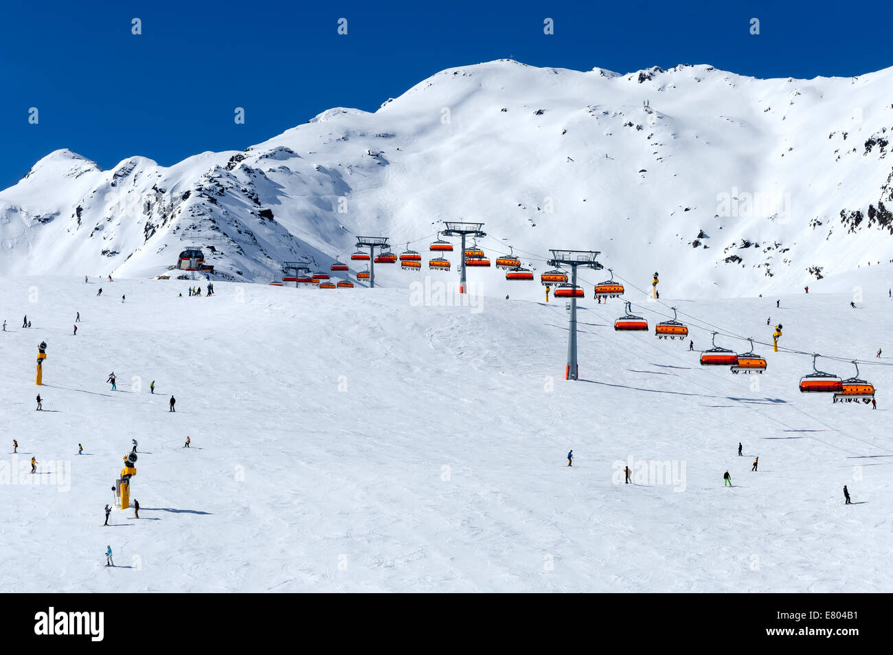 Skifahrer und orange Sessellift im alpinen Skigebiet Sölden im Ötztal Alpen, Tirol, Österreich Stockfoto