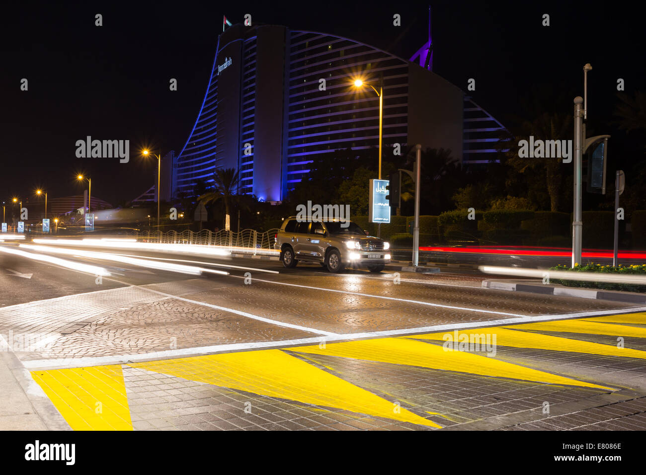 Straßen von Dubai in der Nacht mit dem Jumeirah Hotel im Hintergrund. Stockfoto