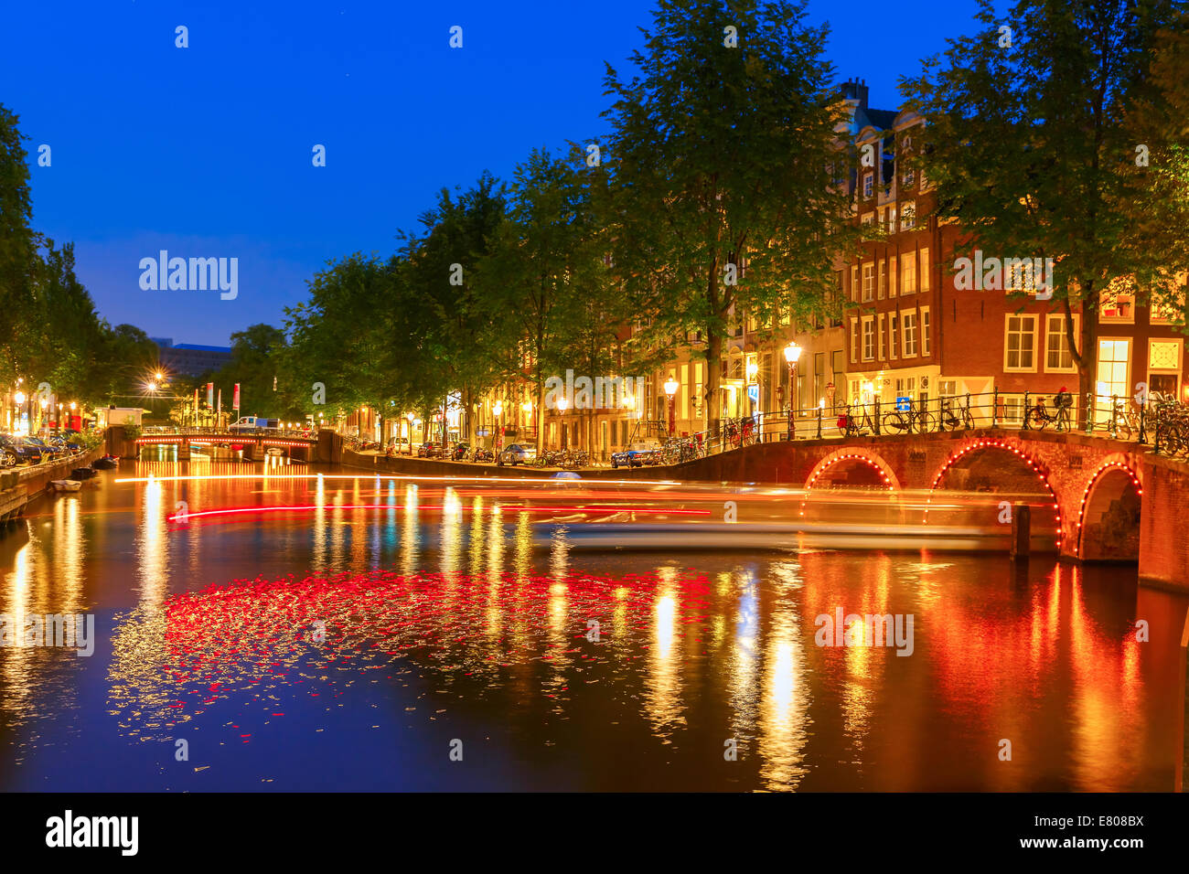 Nacht-Stadtansicht von Amsterdam Canal mit Brücken und leuchtende track aus dem Boot, Holland, Niederlande. Stockfoto