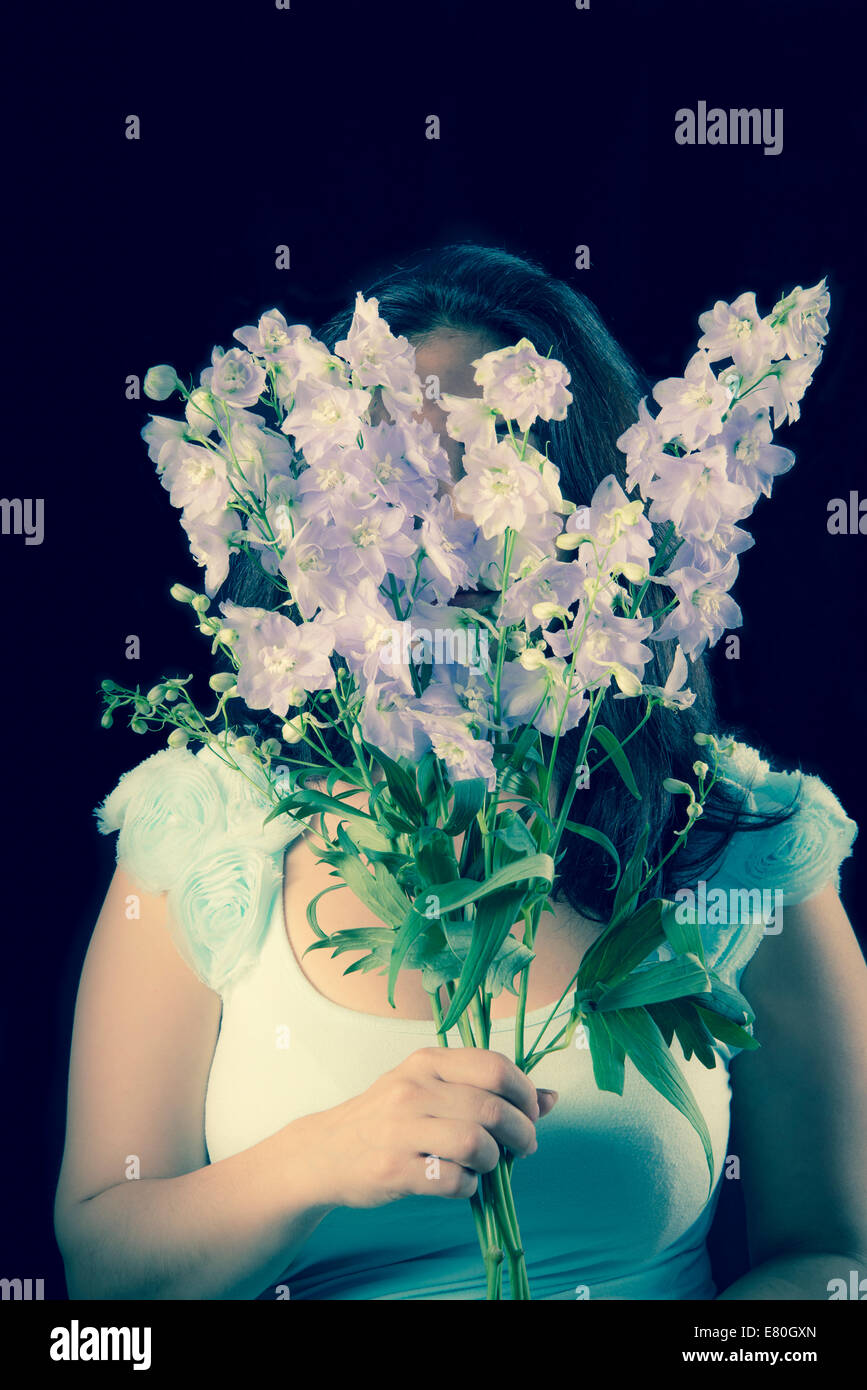 Frau mit Blumen vor ihr Gesicht Stockfoto