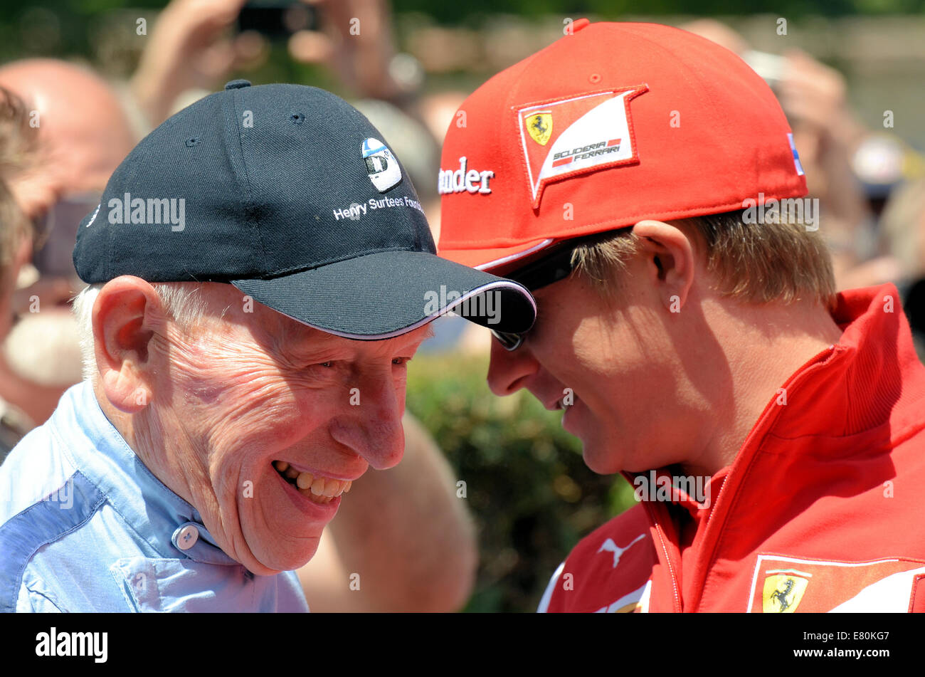 Veteran Fahrer John Surtees Witze mit aktuellen Formel-1-Fahrer Kimi Räikkönen. Junge und alte Rennfahrer sprechen in Gruben in Goodwood Festival Stockfoto