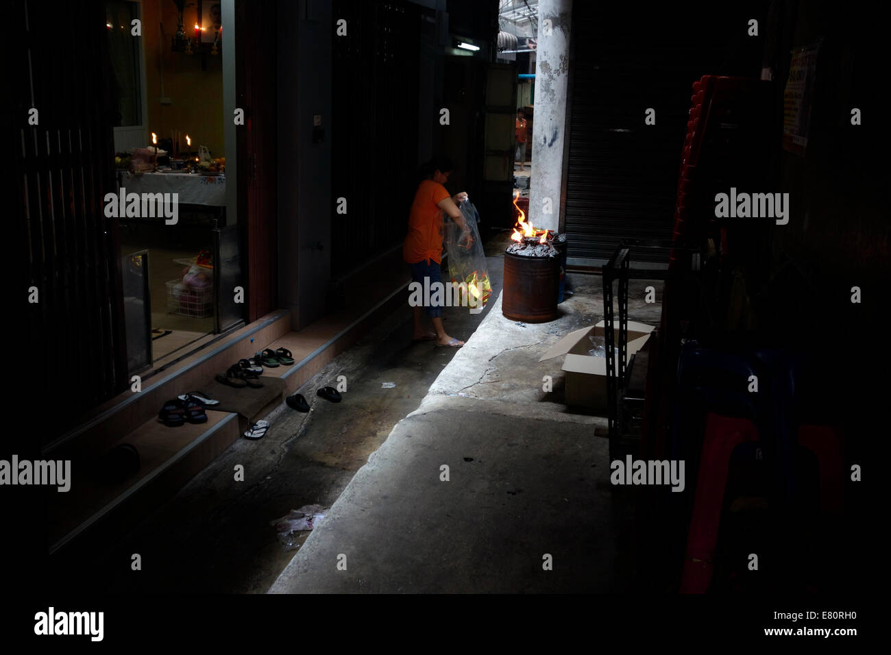 Chinesische Dame brennt während der Ferien bietet. Chinesisches Neujahr in Seitengasse von Bangkok Stockfoto