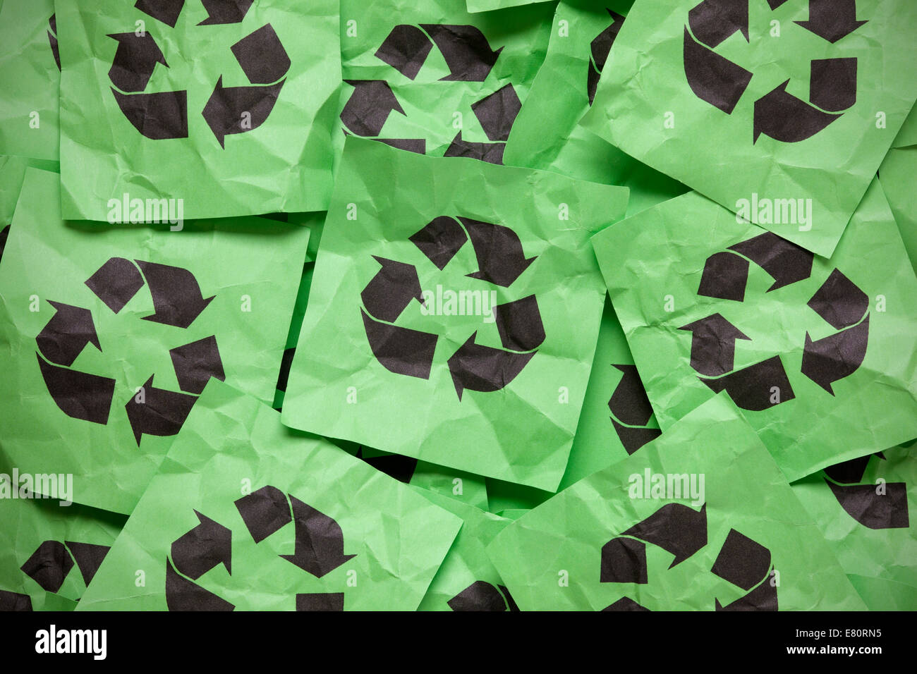 Haufen von сrumpled grünen Notizen auf Papier mit Recycling-Symbolen. Stockfoto