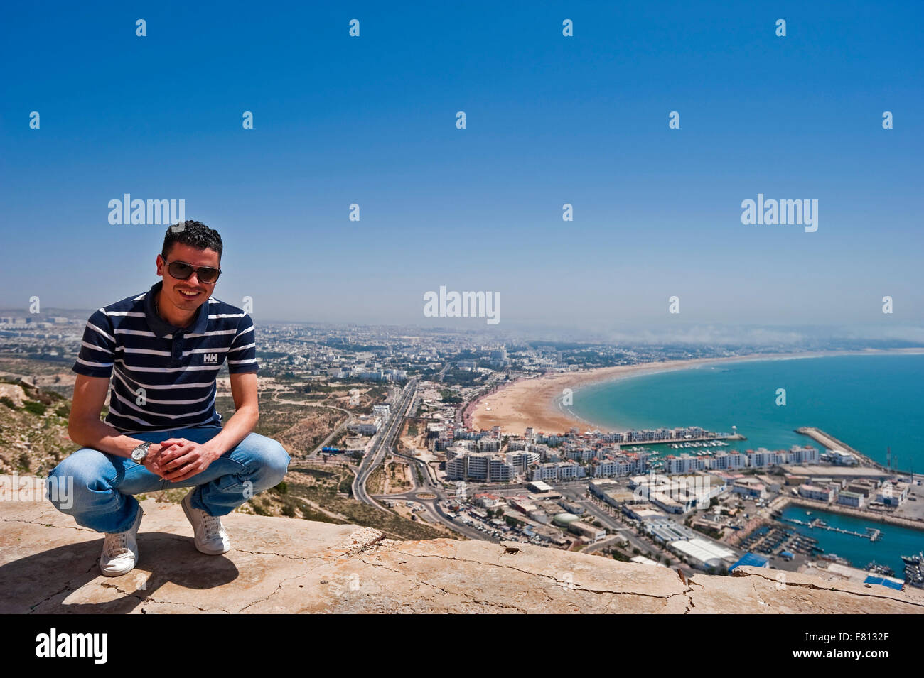 Horizontale Porträt eines jungen marokkanischen Mannes mit einer Luftaufnahme in seiner Heimatstadt von Agadir Stockfoto