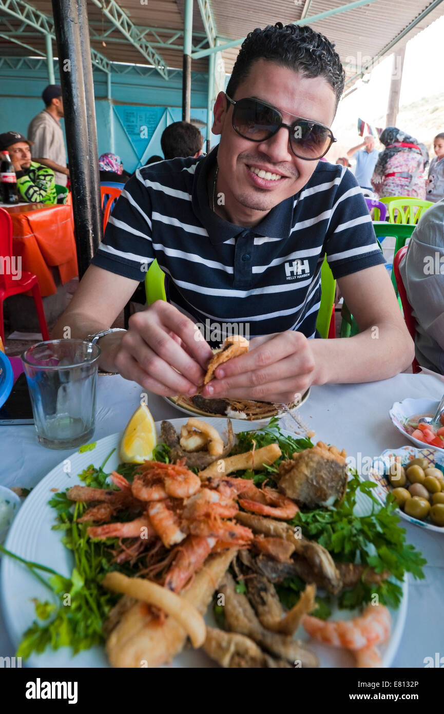 Vertikale Porträt einer jungen marokkanischen Mann essen Meeresfrüchte mit seinen Händen. Stockfoto