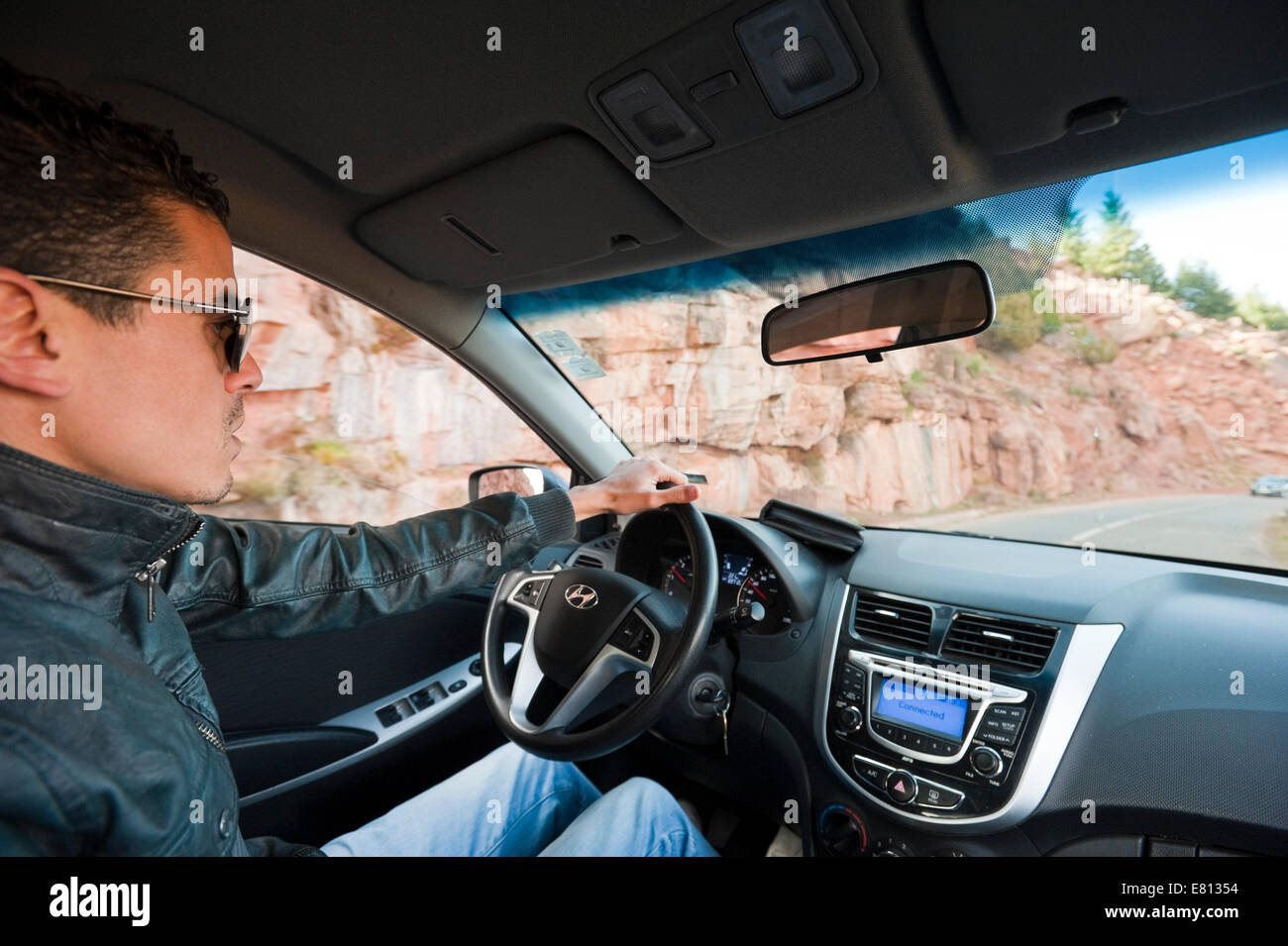 Horizontale Porträt eines jungen marokkanischen Mannes Autofahren linken Antrieb im hohen Atlas-Gebirge in Marokko. Stockfoto