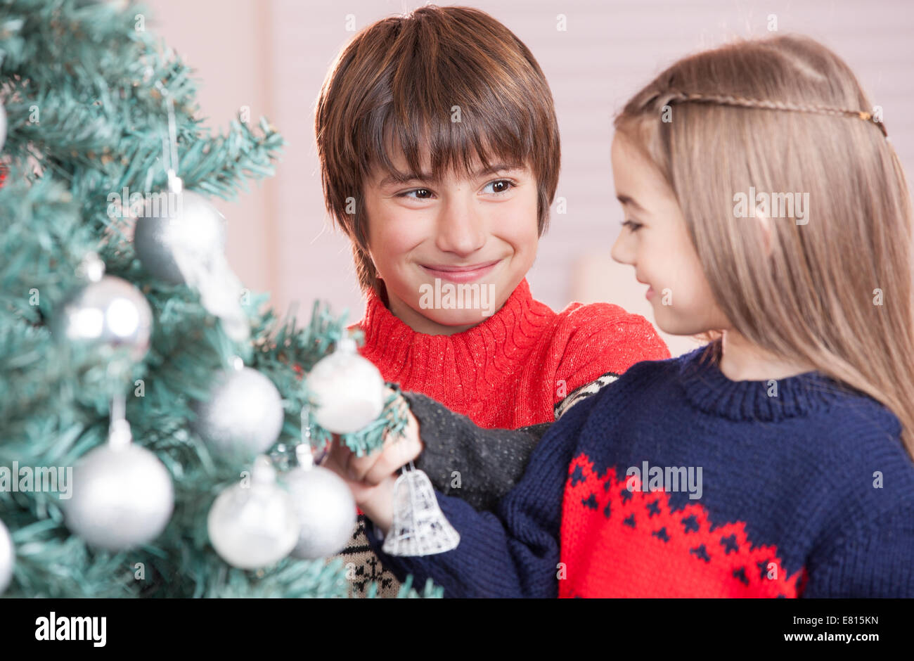 Bruder und Schwester Weihnachten unter dem klassischen Baum zu Hause genießen. Stockfoto