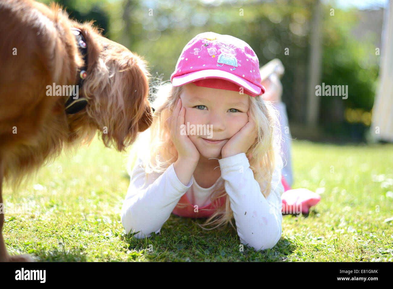 Fünf Jahre altes Mädchen posiert in den Garten lächelnd in die Kamera mit einem Haustier Hund wandern in Schuss Stockfoto
