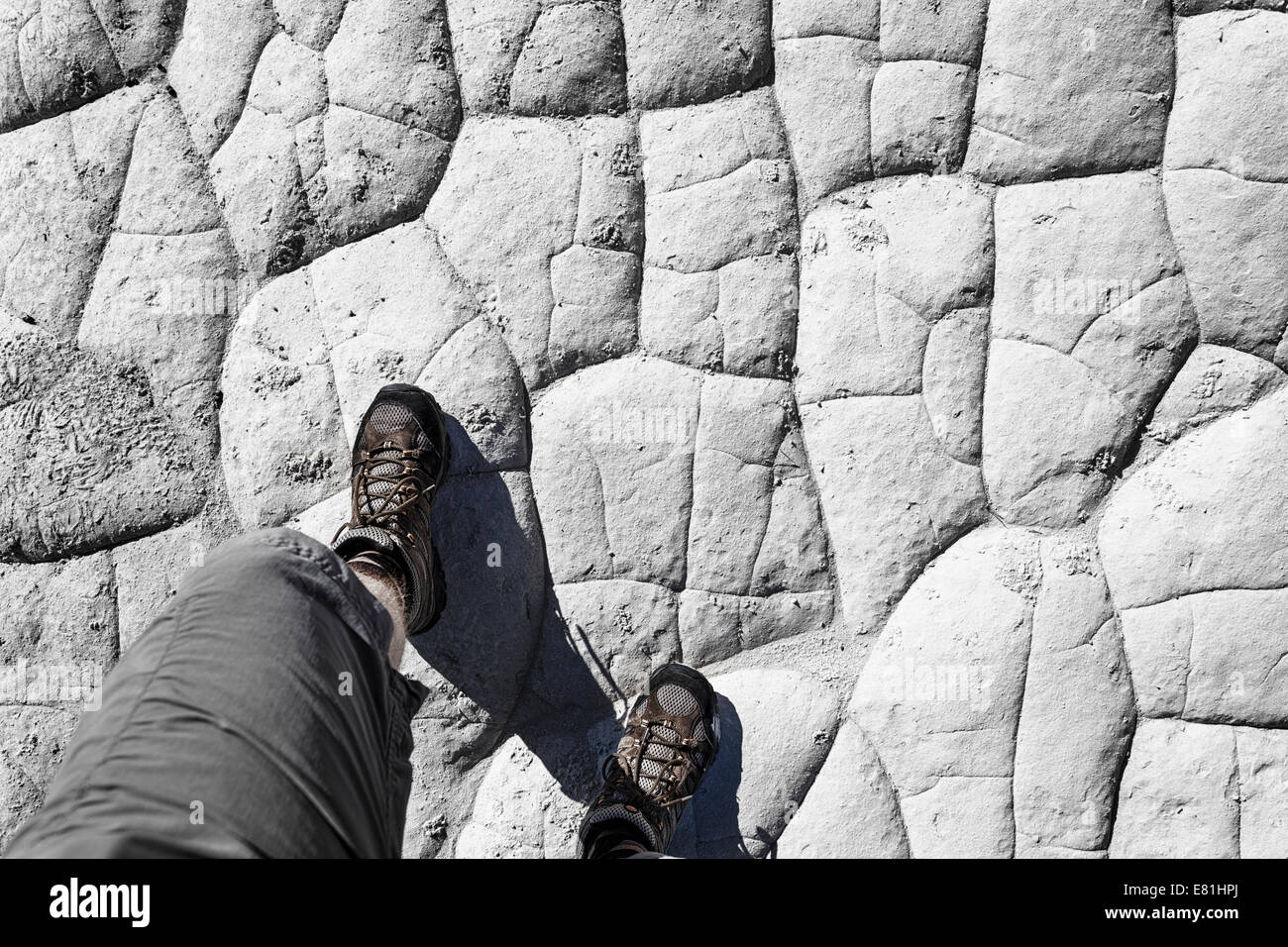 Füße mit Wanderschuhen auf getrockneten Lehm-Boden. Stockfoto
