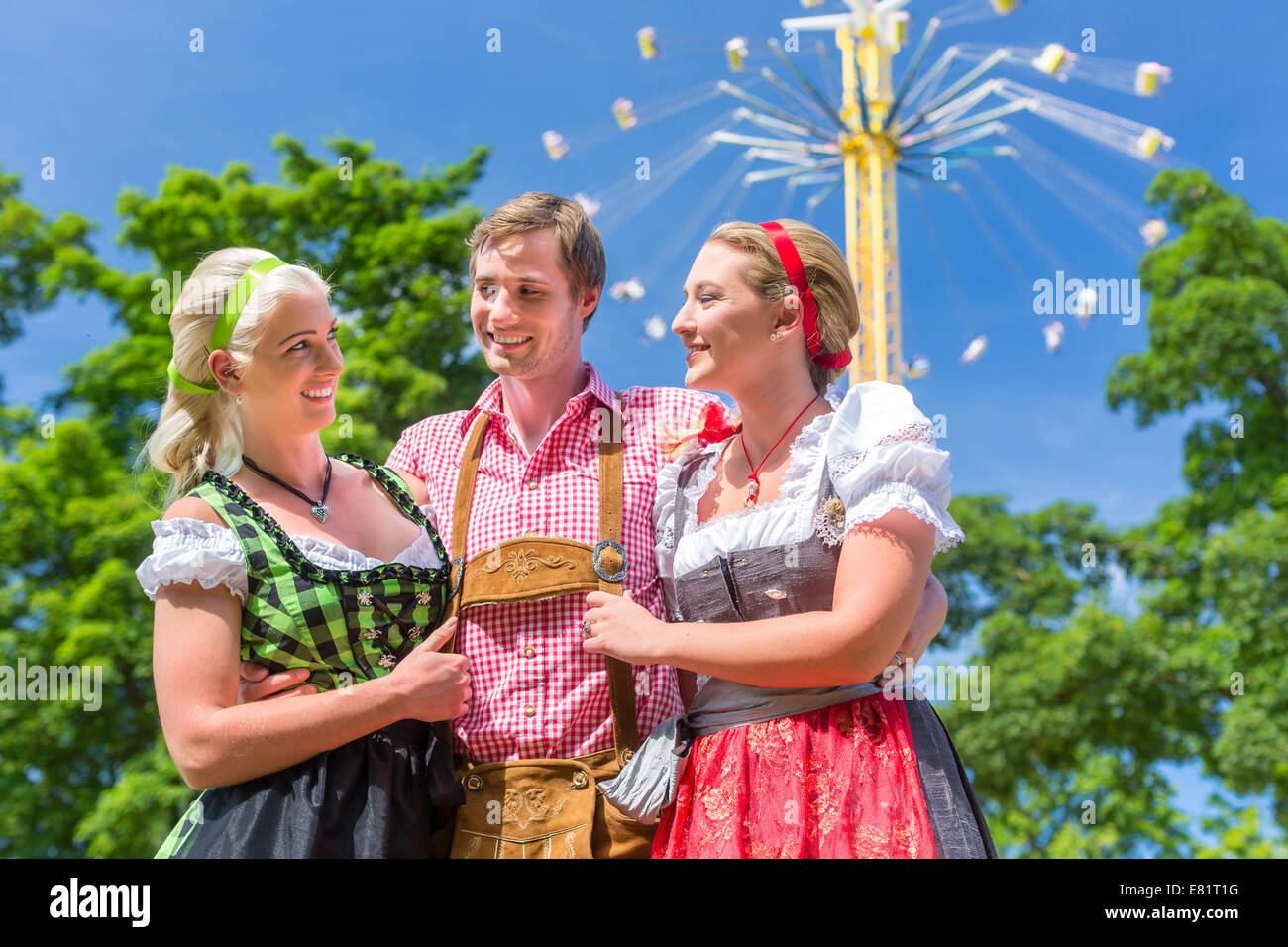 Frauen Freunde besuchen bayerischen Volksfest im Dirndl stehen vor Karussell Stockfoto