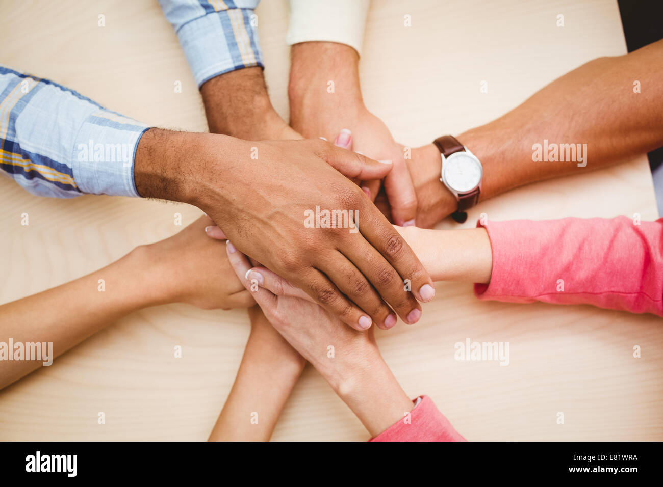 Geschäftsleute, die ihre Hände zusammen auf den Tisch legen Stockfoto