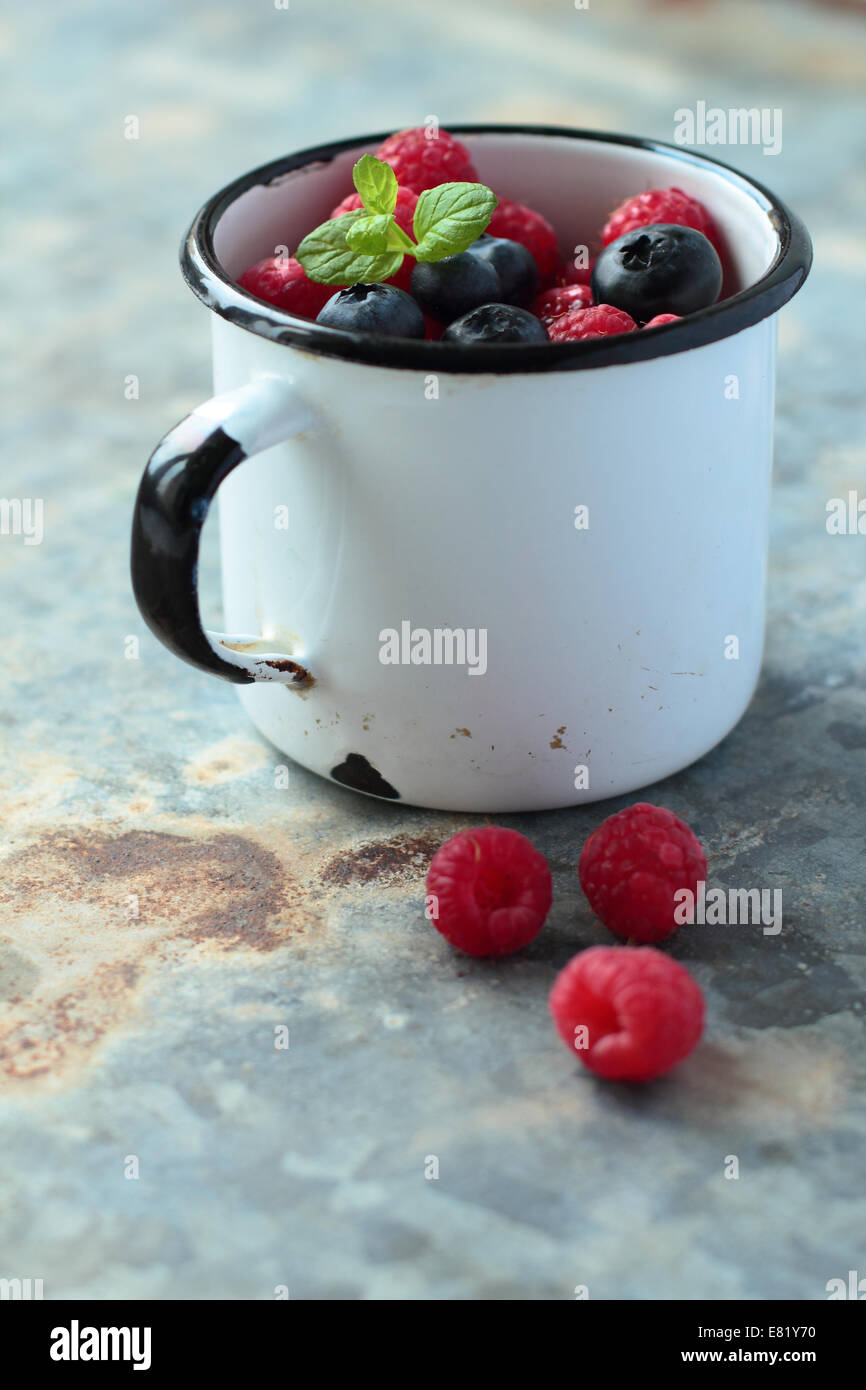 Alte Zinn Emaille Becher mit frischen Früchten Stockfoto