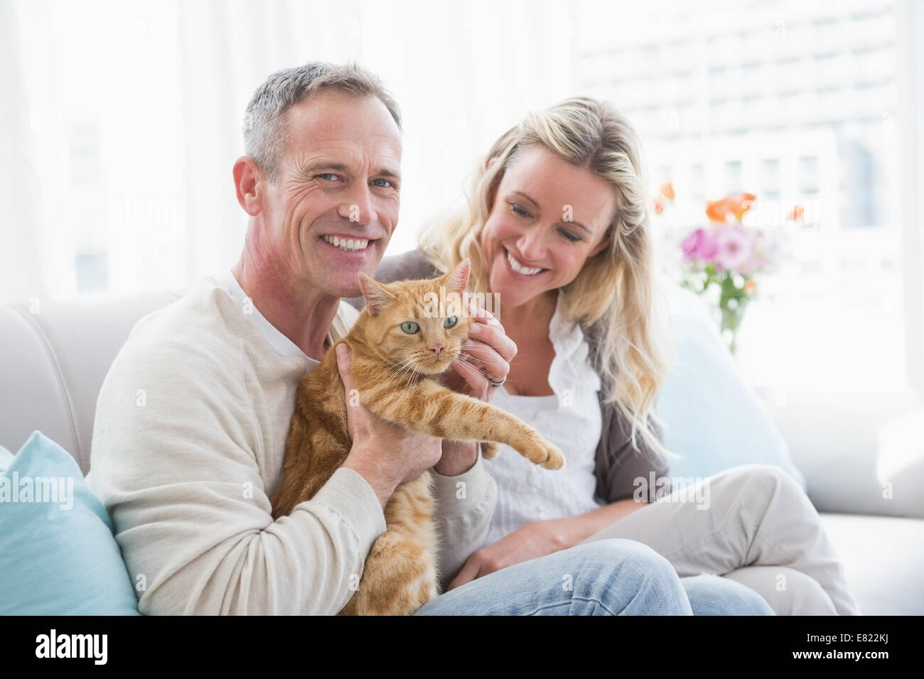 Lächelnde paar streicheln ihre Gringer Katze auf der couch Stockfoto