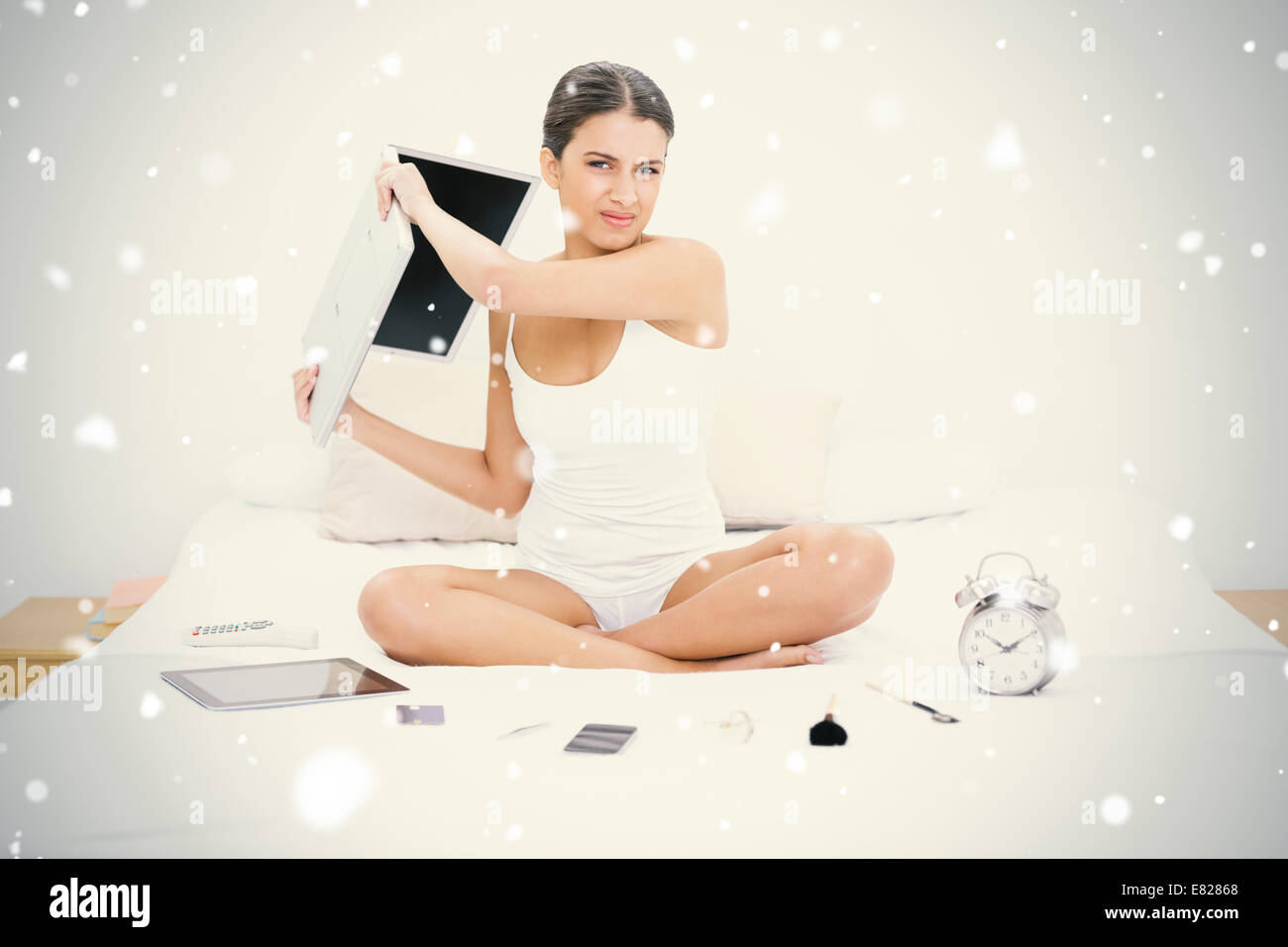 Wütende junge braun behaart Modell in weißen Schlafanzug werfen ihr laptop Stockfoto