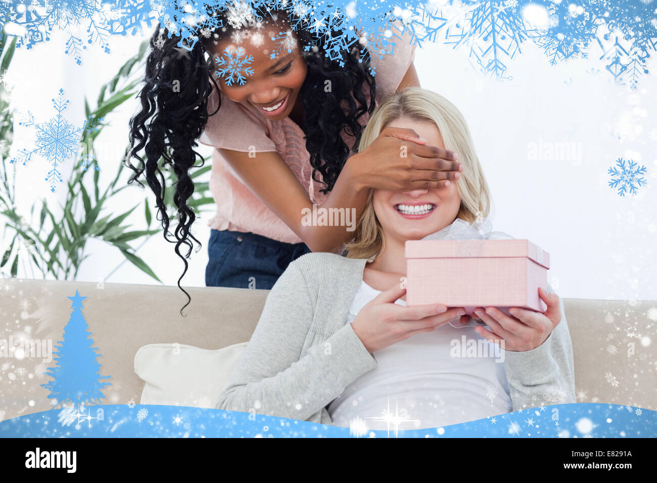 Frau hält ein Geschenk hat ihre Augen von ihrem Freund blockiert Stockfoto