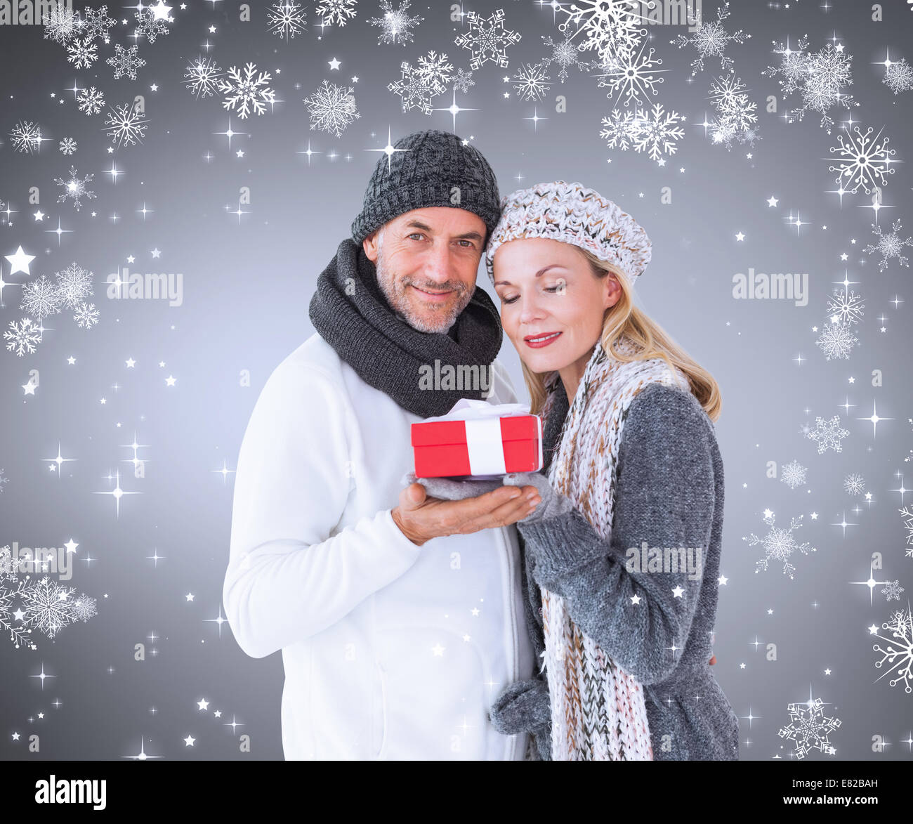 Zusammengesetztes Bild von happy Winter paar mit Geschenk Stockfoto